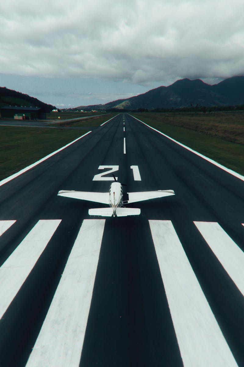 A small airplane on a runway ready for takeoff with scenic mountains in the background.
